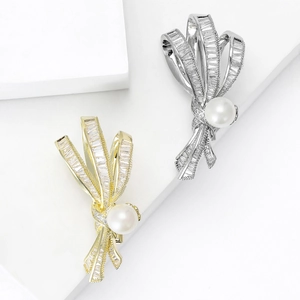 Broche nœud élégante en or et argent avec perle centrale et pierres de zircon brillantes
