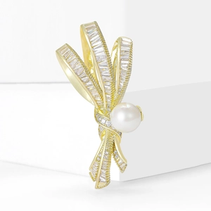 Broche nœud dorée élégante avec cristaux de zircone et détail de perle blanche centrale