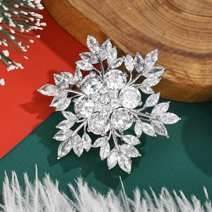 Sparkling zircon snowflake brooch pin with silver metal base on festive winter background