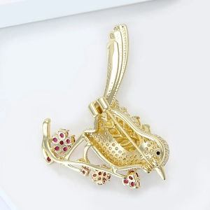 Detailed back view of bird brooch showing hollow gold plating and secure safety pin clasp