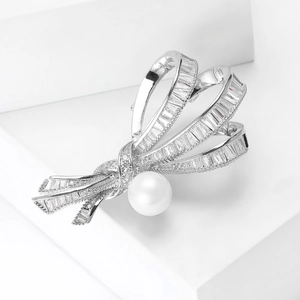 Détail d'une broche nœud en argent sertie de zircons avec une perle blanche lustrée