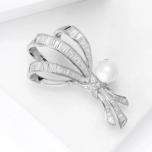 Vue macro d'une broche nœud en argent sertie de zircons et d'une perle blanche élégante