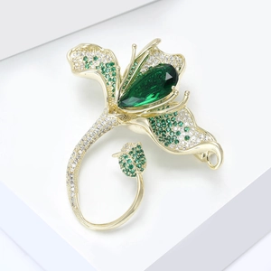 Gros plan d'une broche magnolia avec cristal vert en forme de goutte sur un socle blanc