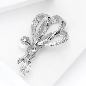 Détails d'une broche nœud argentée avec zircons micropavés et perle élégante