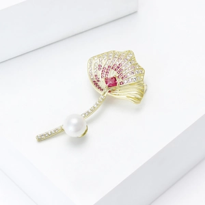 Golden ginkgo leaf brooch with pink cubic zirconia, red gem, and white pearl accent