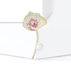 Macro shot of ginkgo leaf brooch with pink zircon crystals and a round white pearl