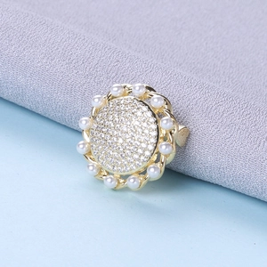 Detailed macro of a vintage gold brooch with clear rhinestones and white pearls