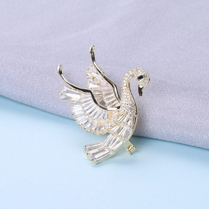 Detail of elegant gold swan brooch with sparkling cubic zirconia on knitted fabric