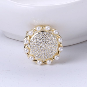 Macro shot of retro sunflower brooch with gold base, white pearls, and zircon crystals