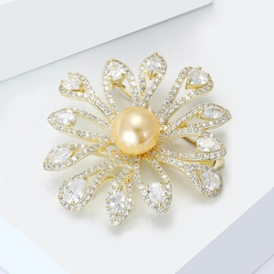 Detailed view of vintage gold sunburst flower brooch with pearls and zircon on white block