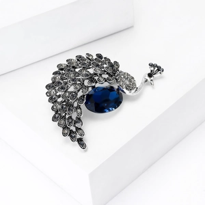 Exquisite silver peacock brooch with a large deep blue crystal and sparkling white rhinestones