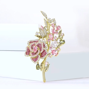 Detailed view of rose flower brooch with pink zircons on elegant white geometric stand