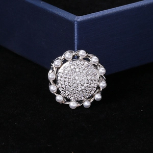 Detail of sunflower brooch with micro-set zircons and faux pearls on black velvet