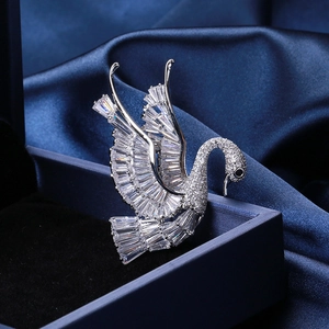 Detailed view of swan brooch with inlaid zircon crystals on a dark blue velvet box