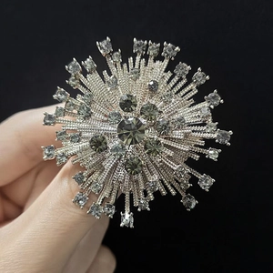 Detail of starburst brooch with dark grey gemstones and silver metal texture
