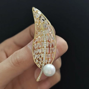Détail d'une broche feuille avec zircons rectangulaires et une grande perle blanche dorée