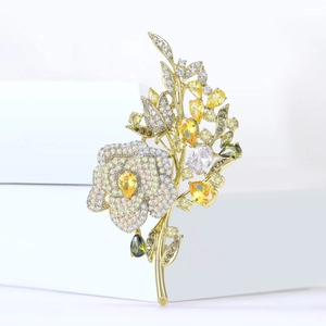 Macro shot of gold floral brooch featuring yellow and green cubic zirconia stones