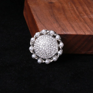 Macro shot of silver-tone sunflower brooch with pavé zircon stones and pearl border