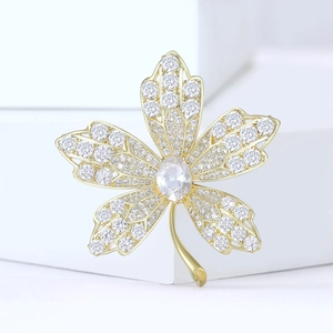 Elegant maple leaf brooch in gold finish with micro-paved white zircons and large center stone