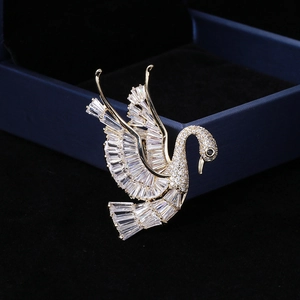 Detailed close-up of golden swan brooch with baguette-cut zircons on a blue velvet gift box