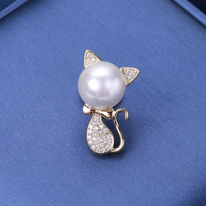 Macro shot of a cat brooch featuring a large white pearl and gold micro-pave zircons