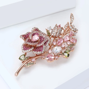 Close-up of rose gold flower brooch with pink zircons and green leaf gemstone details
