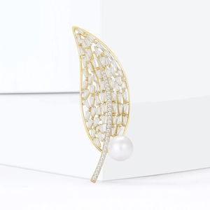 Broche en forme de feuille avec zircons et une grande perle ronde sur fond blanc