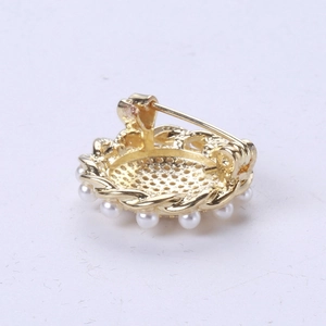 Detail showing the golden metal base and circular pearl setting of the sunflower brooch