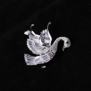 Macro shot of silver swan brooch with clear zircons and black eye on black background