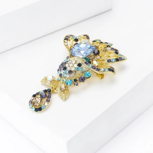 Macro shot of gold-plated fish brooch with blue crystals and water drop pendant detail