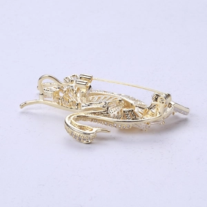 Detailed close-up of golden swan brooch with white zircon stones and safety pin clasp