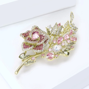 Detailed macro view of gold flower brooch with inlaid pink and green zircon crystals