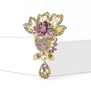 Exquisite gold floral brooch with pink and purple crystals on a white pedestal