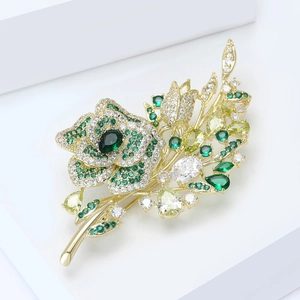 Macro shot of gold floral brooch featuring green crystals and sparkling zircon leaves