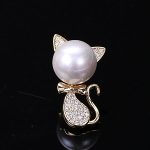 Macro shot of a cat brooch with a large pearl head and zircon-studded gold-tone body