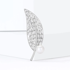 Broche feuille avec zircons argentés et perle sur fond géométrique blanc