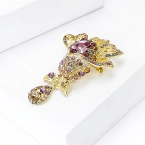 Close-up of golden fish brooch featuring purple crystals and detailed Czech rhinestones