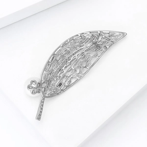 Détail macro d'une broche feuille argentée avec métal évidé et zircons brillants