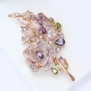Macro shot of rose gold flower brooch with purple and green zircon crystals detail