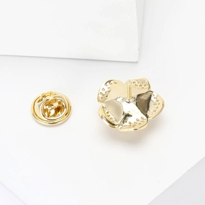 Close-up of golden rose brooch with textured five-petal design and metal clutch back