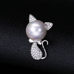 Macro shot of silver cat brooch with micro-paved zircons and large round white pearl detail