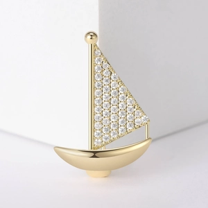 Élégante broche voilier dorée avec micro-pavé de zircons sur fond géométrique blanc