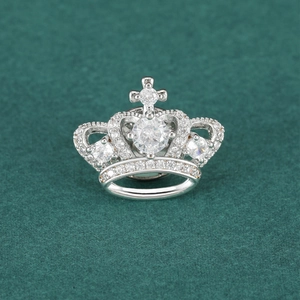 Luxury crown brooch with sparkling zircons and cross detail on dark green fabric
