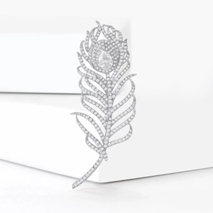 Détail d'une broche plume élégante avec diamants pavés et pierre centrale en poire
