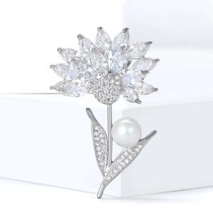 Eleganter silberner Blumenanstecker mit Zirkonia und weißer Perle auf weißem Sockel