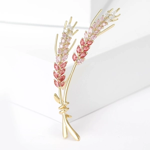 Detailed macro view of gold wheat brooch with colorful marquise crystals on white blocks