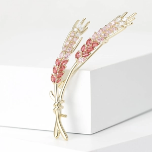 Detail of elegant wheat ear brooch with pink and red crystals on golden metal base