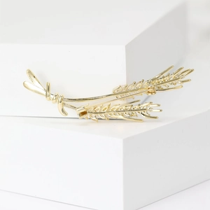 Detail of elegant gold wheat stalk brooch with polished finish on geometric block