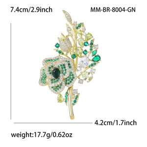 Elegant rose flower brooch with green cubic zirconia and golden finish on white backdrop
