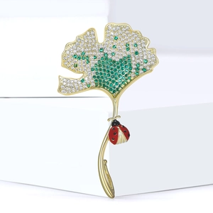 Gouden ginkgoblad broche met groene zirkoon verloop en lieveheersbeestje detail